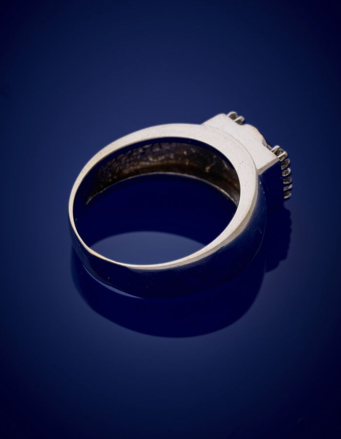 BAGUE en or gris (750‰) serti d'une pierre bleue (égrisures), épaulée de six pa…