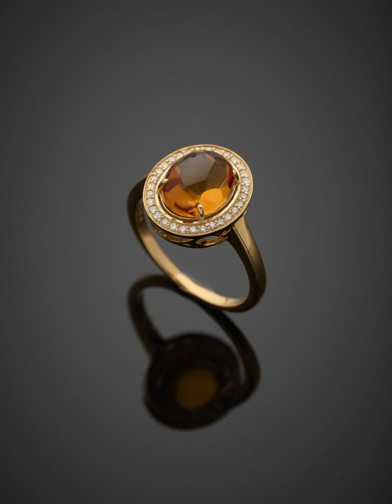 BAGUE en or jaune (375‰) 9 carats, serti d'une citrine cabochon ovale, entourée…
