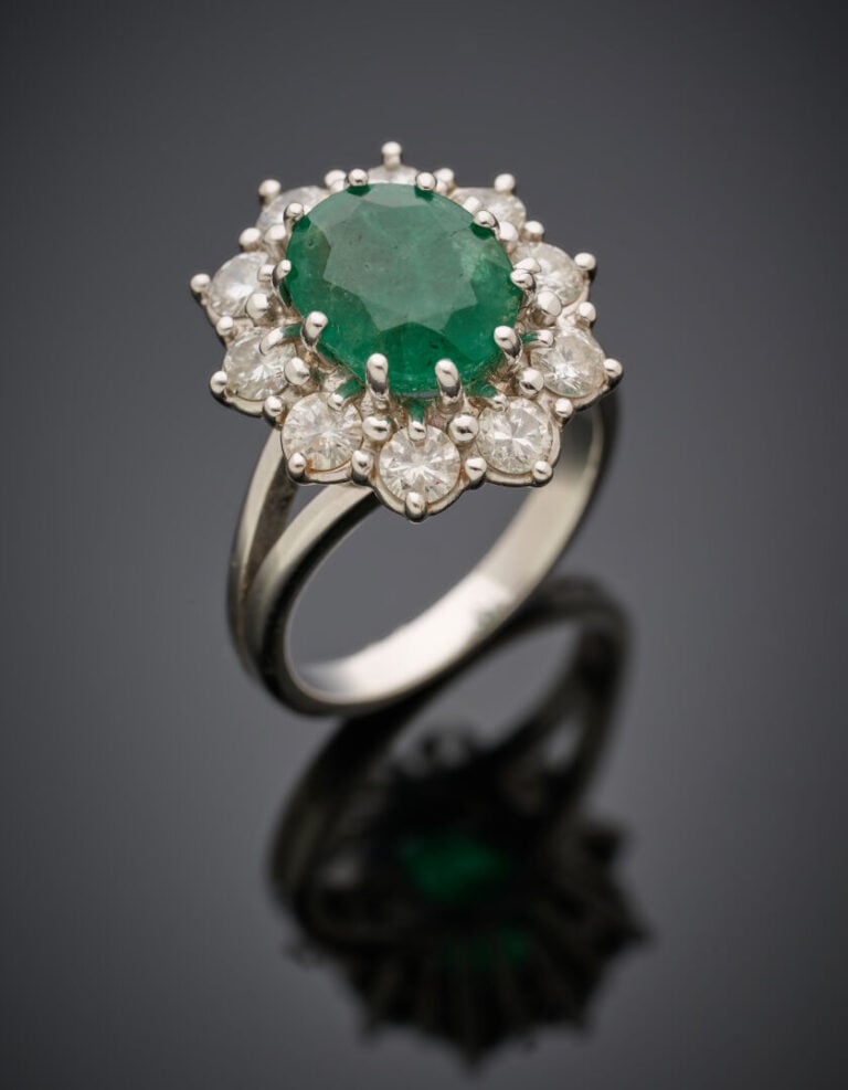 BAGUE "marguerite" en or gris (750‰) serti d'une émeraude ovale, entourée de di…