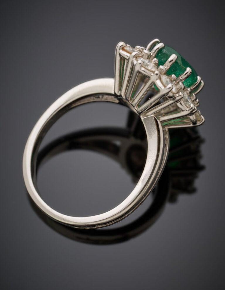 BAGUE "marguerite" en or gris (750‰) serti d'une émeraude ovale, entourée de di…