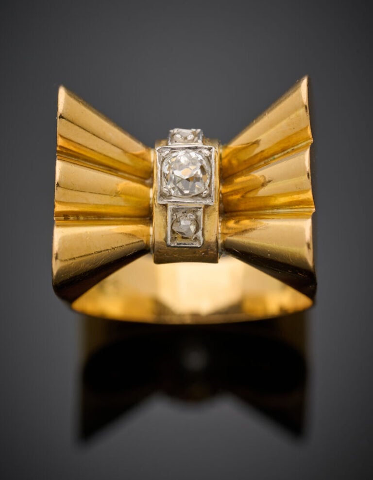 BAGUE "nœud" stylisé en platine (950‰) et or jaune (750‰) godronné, centrée d'u…