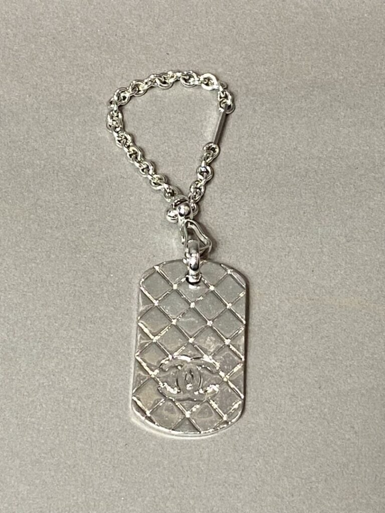 CHANEL circa 2004 - Porte-clefs chaîne en métal argenté retenant un pendentif d…