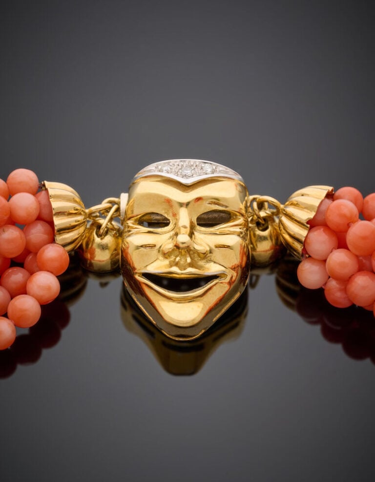 COLLIER composé de 7 rangs de perles de corail. Fermoir "masque vénitien" en or…