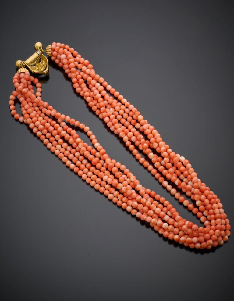 COLLIER composé de 7 rangs de perles de corail. Fermoir "masque vénitien" en or…