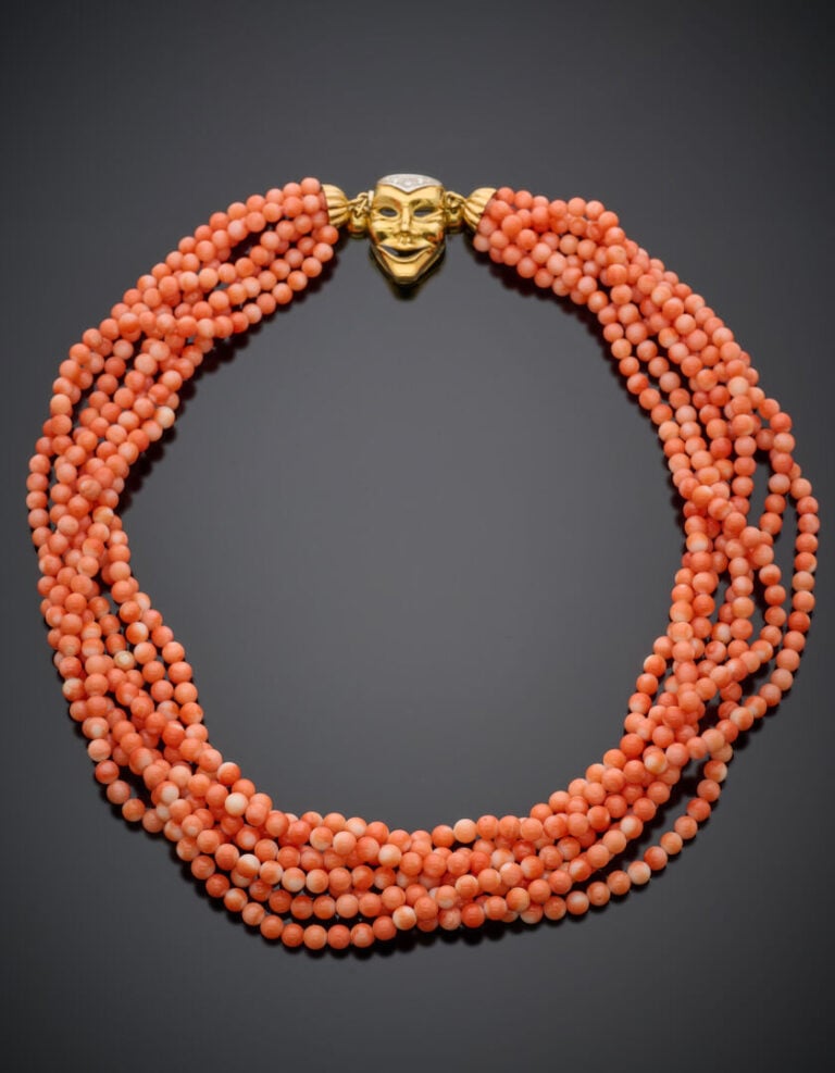COLLIER composé de 7 rangs de perles de corail. Fermoir "masque vénitien" en or…