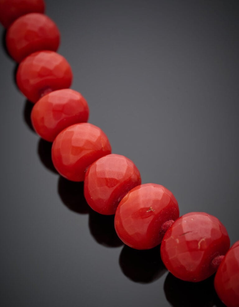 "COLLIER composé de perles de corail rouge facetté, en chute. Fermoir en argent…