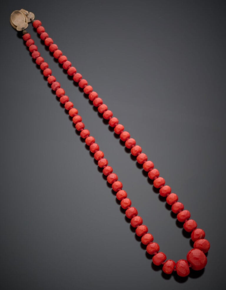 "COLLIER composé de perles de corail rouge facetté, en chute. Fermoir en argent…