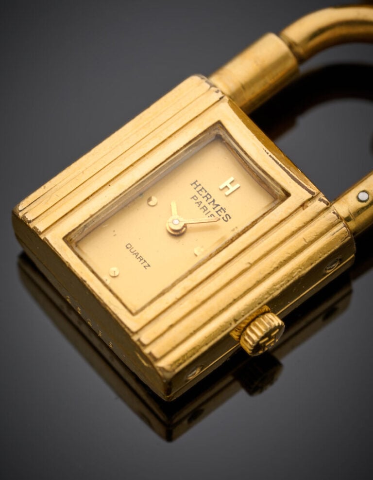 HERMES - BRACELET MONTRE "Kelly" en métal doré composé d'un bracelet en cuir. -…