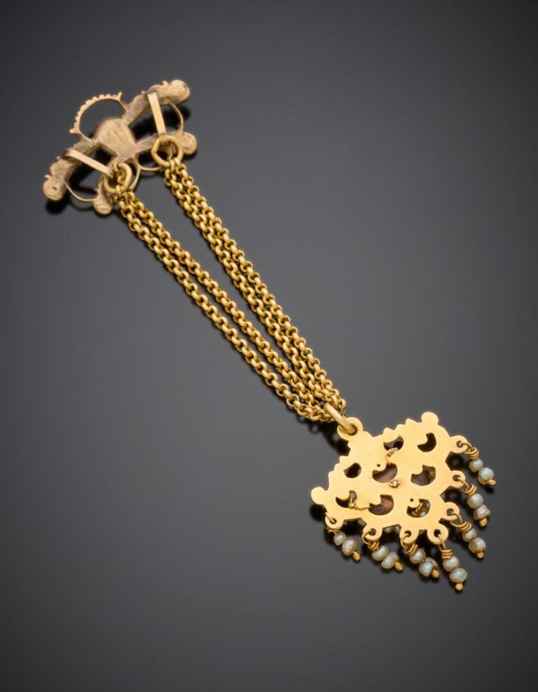 PENDENTIF en or jaune (750°/°°) repercé, ciselé, serti de grenats et pierres ro…