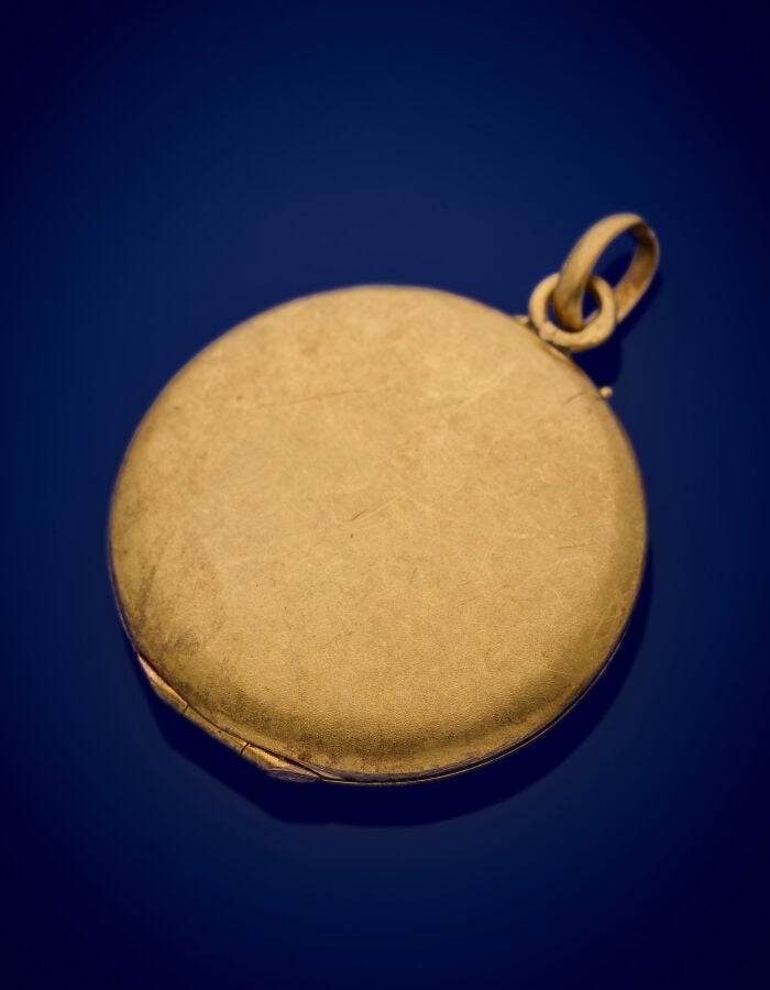 PENDENTIF porte-souvenir circulaire en or jaune (750‰) ciselé, serti d'une pier…