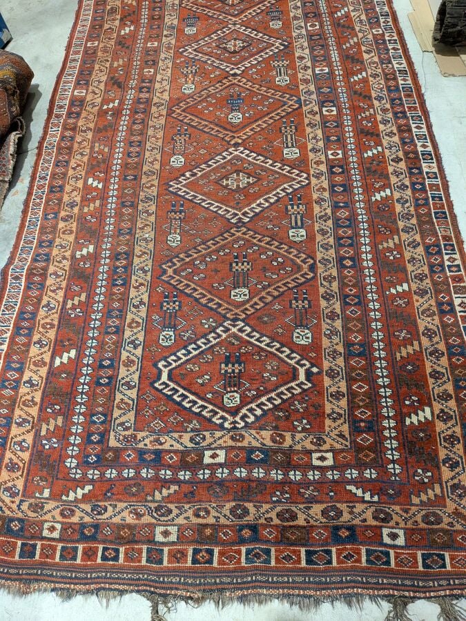 Grand tapis oriental à 6 médaillons losangiques sur fond rouge agrémenté de 13…