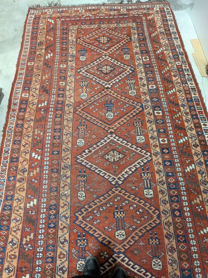 Grand tapis oriental à 6 médaillons losangiques sur fond rouge agrémenté de 13…