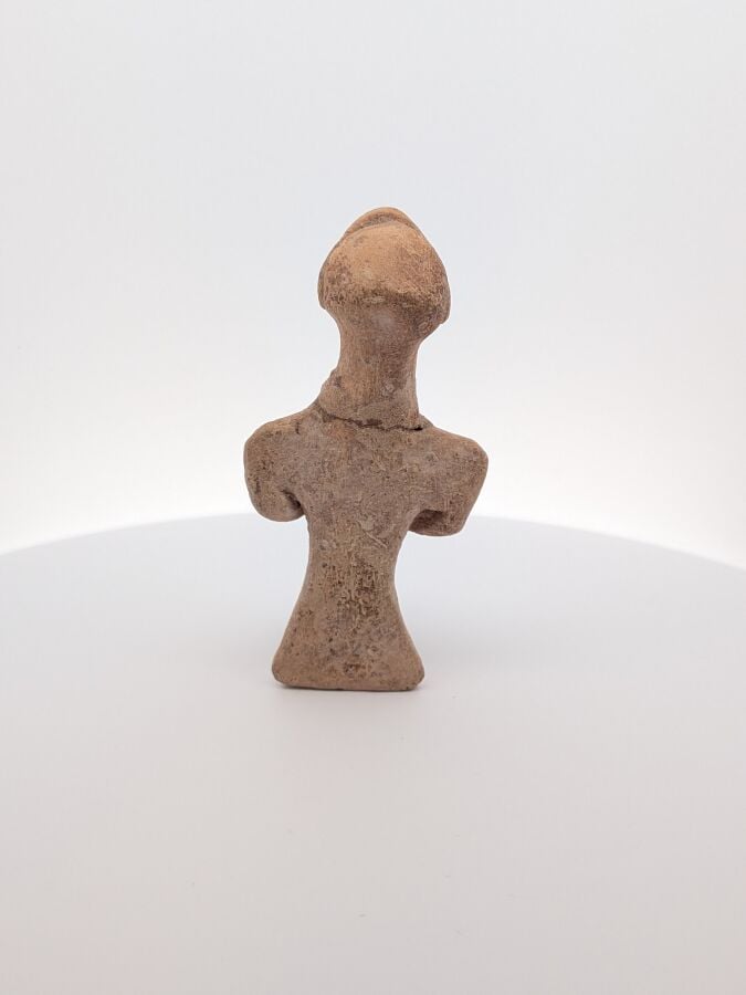 Figurine assise stylisée, tenant un instrument indéterminé. - Terre cuite beige…