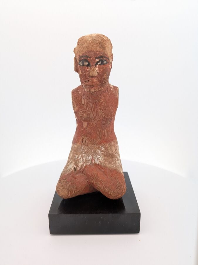 Figurine masculine, les jambes en tailleur, il est vêtu d'un pagne court et d'u…