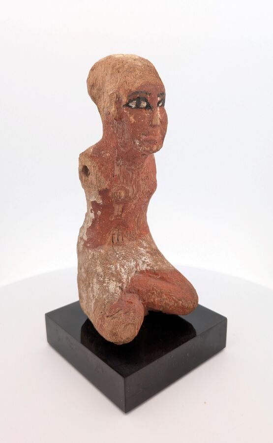 Figurine masculine, les jambes en tailleur, il est vêtu d'un pagne court et d'u…
