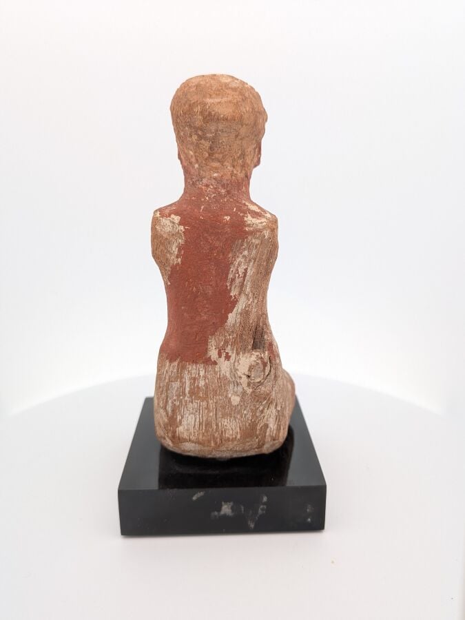 Figurine masculine, les jambes en tailleur, il est vêtu d'un pagne court et d'u…
