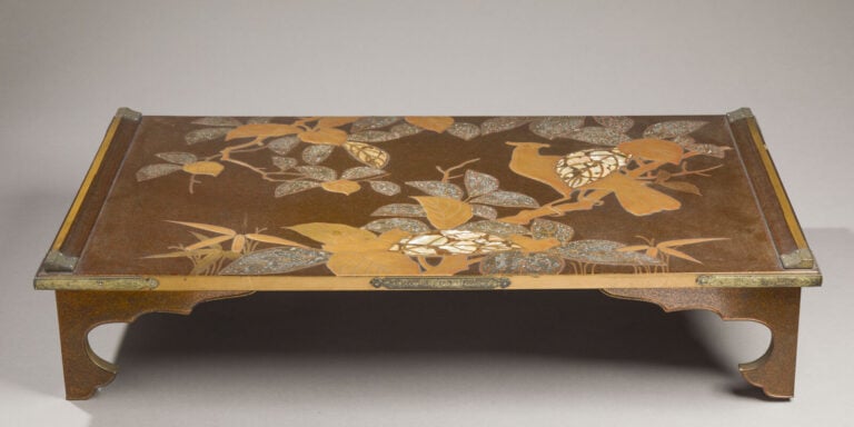 JAPON - XXème siècle - Plateau bas quadripode laqué or sur fond noir à décor d'…