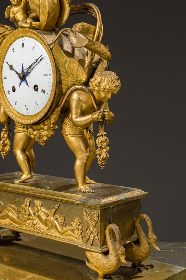 Pendule aux amours ailés en bronze doré présentant deux amours portant - une gu…