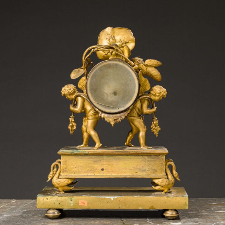 Pendule aux amours ailés en bronze doré présentant deux amours portant - une gu…
