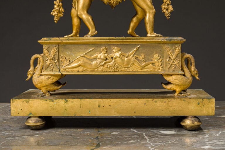 Pendule aux amours ailés en bronze doré présentant deux amours portant - une gu…