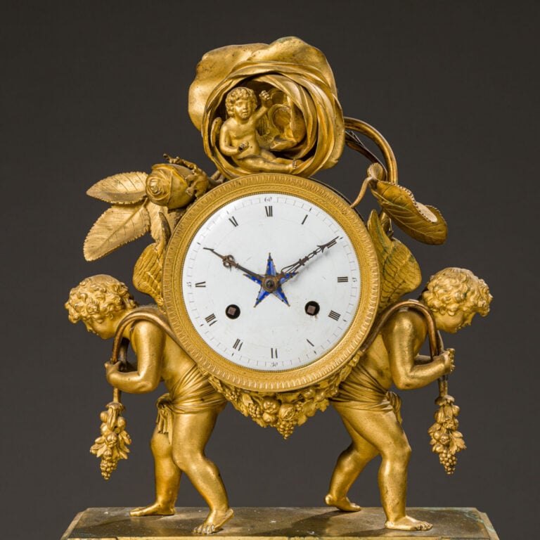 Pendule aux amours ailés en bronze doré présentant deux amours portant - une gu…