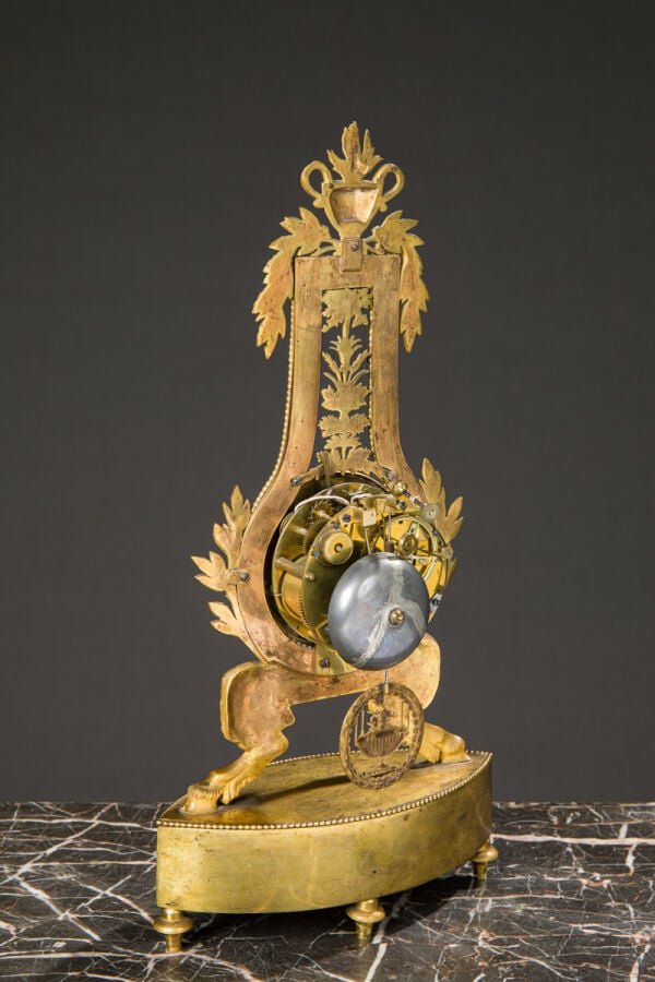 Pendule Lyre en bronze ciselé et doré reposant sur des pieds jarets et sommé d'…