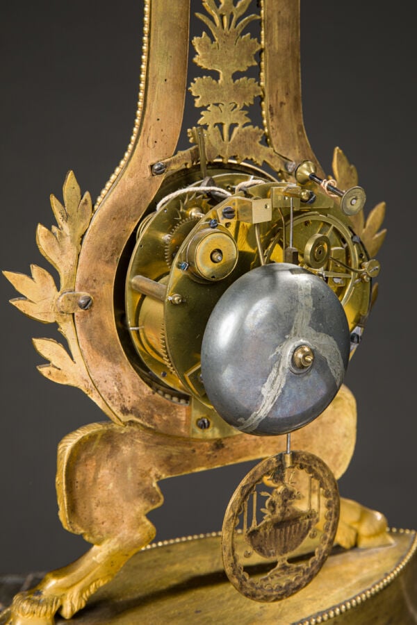Pendule Lyre en bronze ciselé et doré reposant sur des pieds jarets et sommé d'…