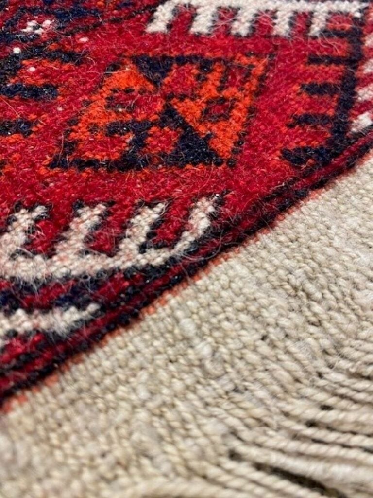 Tapis en laine type Boukhara noué à la main à motifs de güls sur fond rouge, bo…