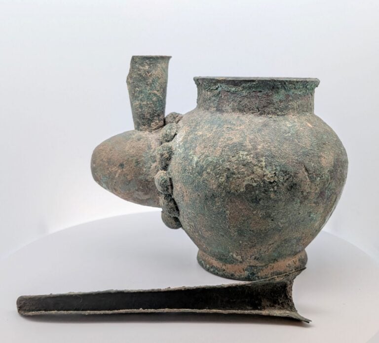 Vase à long bec verseur en gouttière présentant à la base un jabot retenu par d…