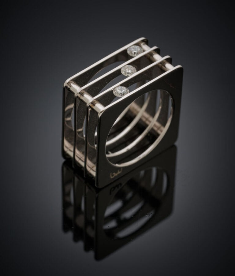 BAGUE "carrée" en or gris (750‰} ajouré, serti de trois diamants taille brillan…