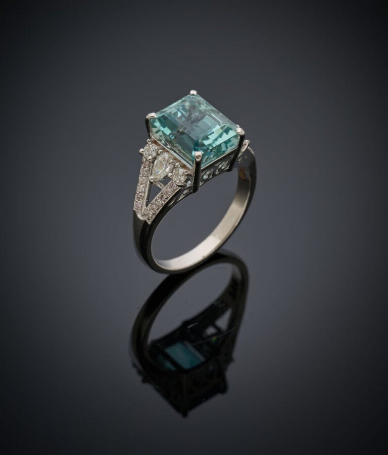 BAGUE en or gris (750‰) serti d'une aigue-marine taillée à degrés, épaulée de d…