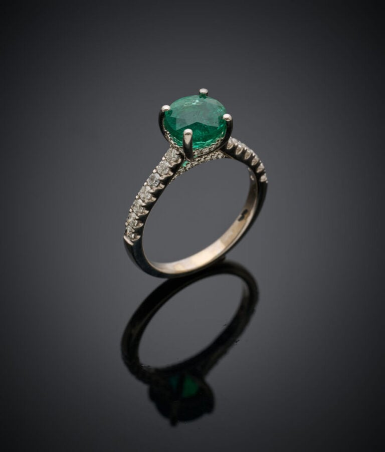 BAGUE en or gris (750‰) serti d'une émeraude ronde, épaulée de diamants taille…