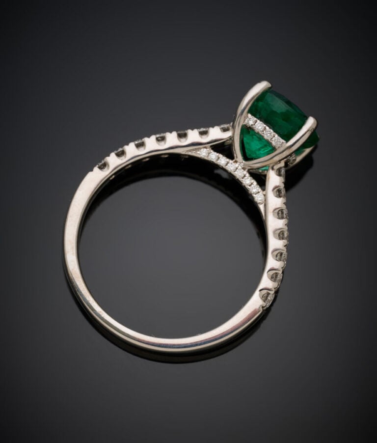 BAGUE en or gris (750‰) serti d'une émeraude ronde, épaulée de diamants taille…
