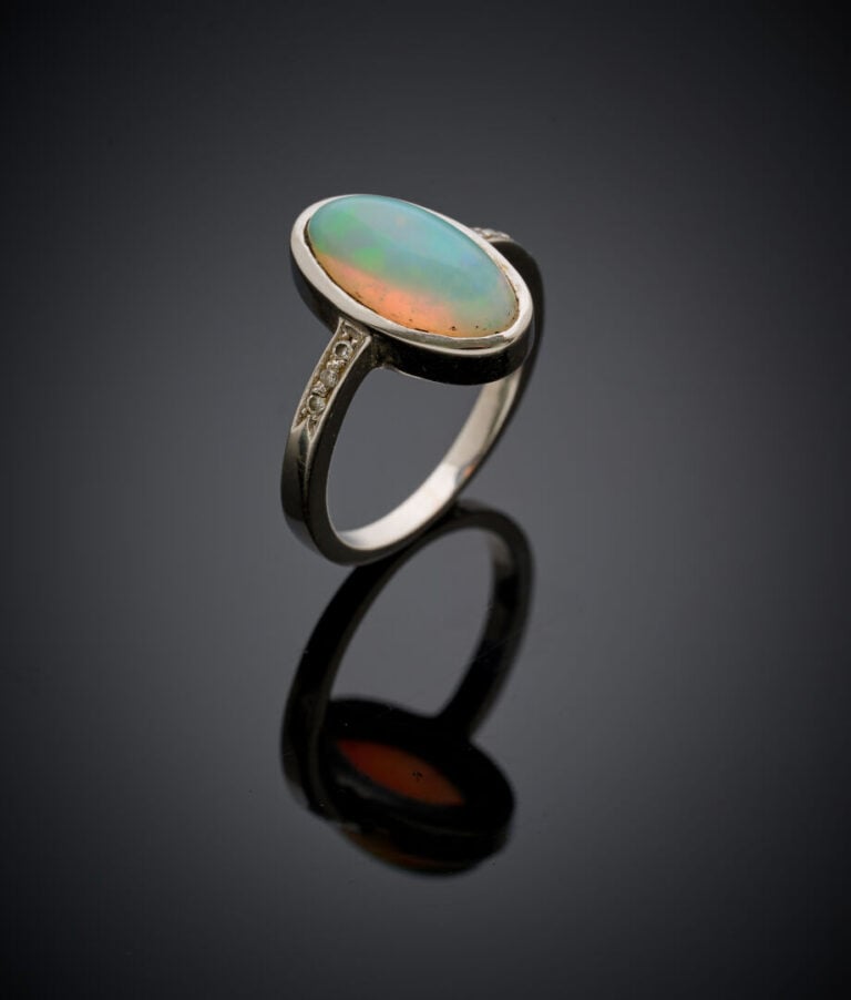 BAGUE en or gris (750‰) serti d'une opale cabochon de forme ovale épaulée de pe…