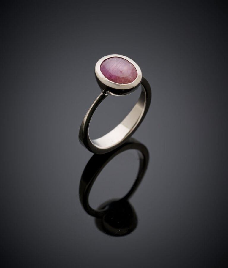 BAGUE en or gris (750‰) serti d'une pierre rouge cabochon étoilée en serti clos…