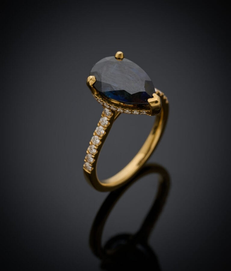 BAGUE en or jaune (750‰) serti d'un saphir foncé de forme poire, entouré et épa…