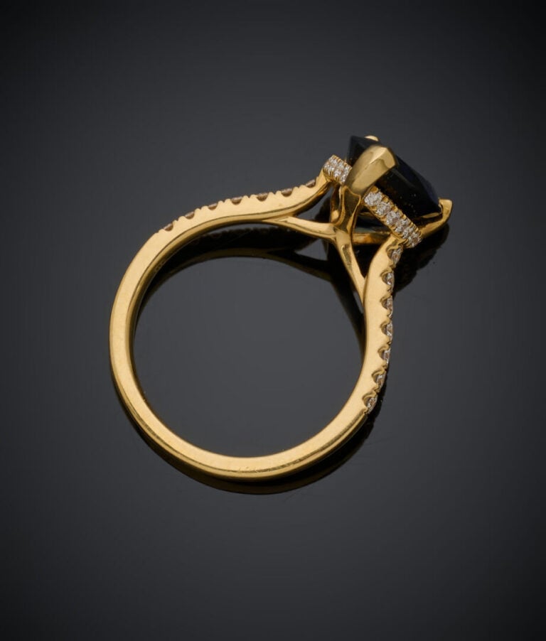 BAGUE en or jaune (750‰) serti d'un saphir foncé de forme poire, entouré et épa…
