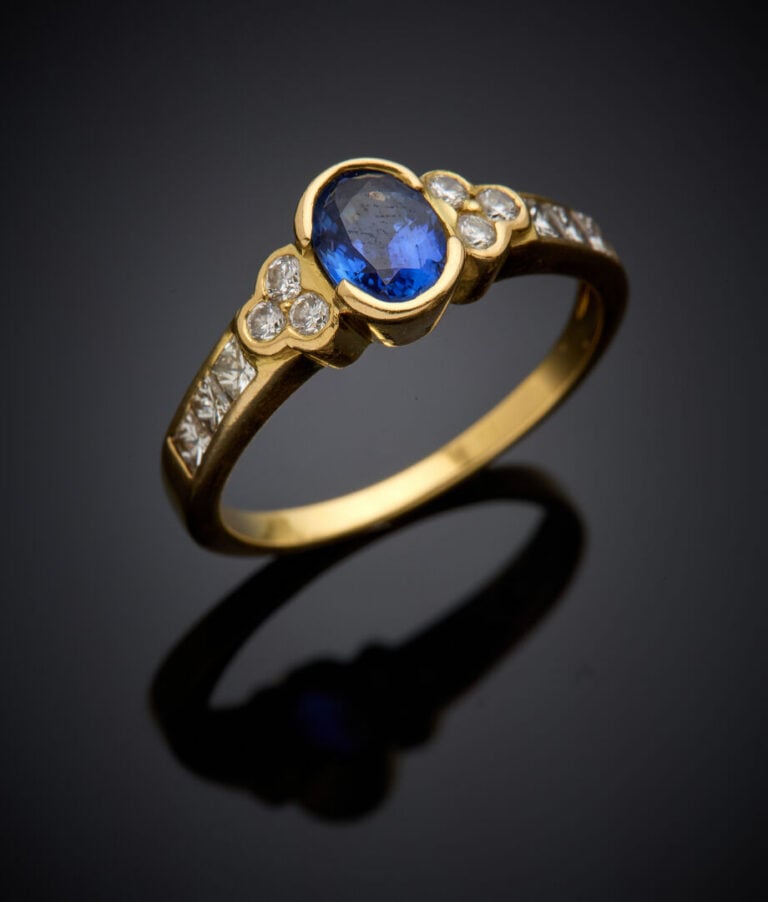 BAGUE en or jaune (750‰) serti d'un saphir ovale (choc) et épaulé de diamants t…