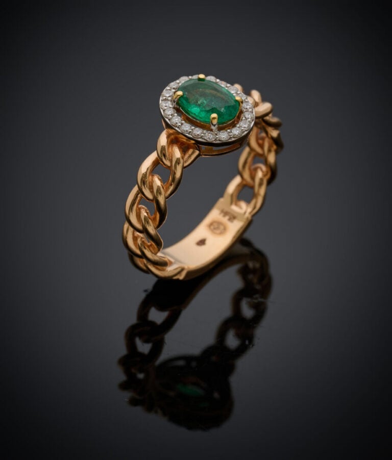 BAGUE "gourmette" en or rose (750‰) ajouré, serti d'une émeraude ovale entourée…
