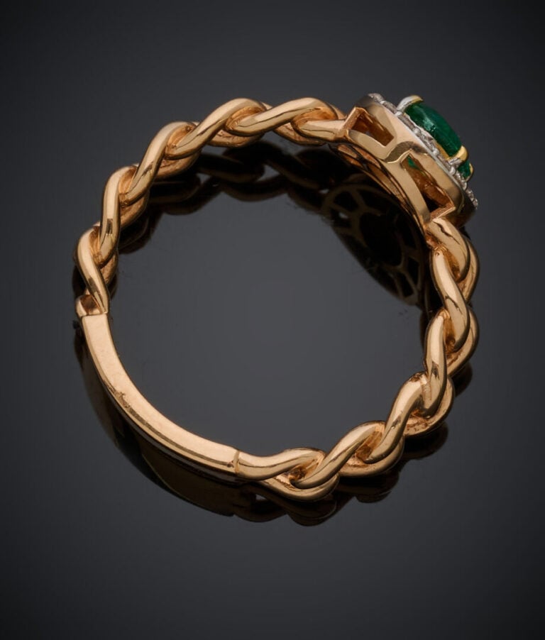 BAGUE "gourmette" en or rose (750‰) ajouré, serti d'une émeraude ovale entourée…