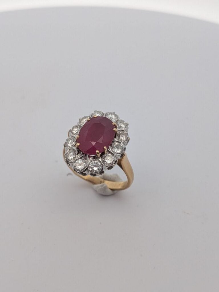 BAGUE "marguerite" en or jaune et or gris (750‰) serti d'un rubis ovale, entour…