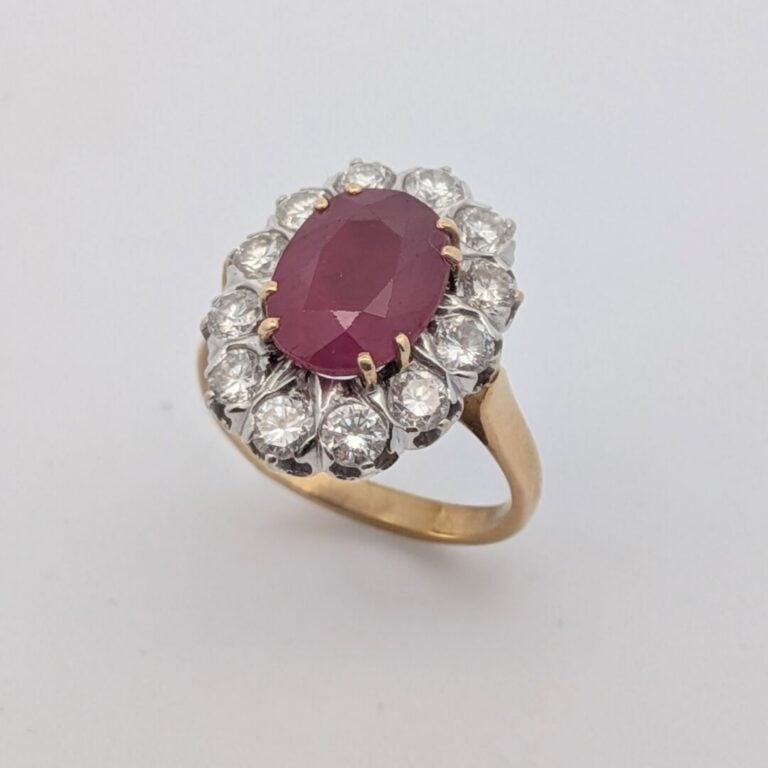 BAGUE "marguerite" en or jaune et or gris (750‰) serti d'un rubis ovale, entour…