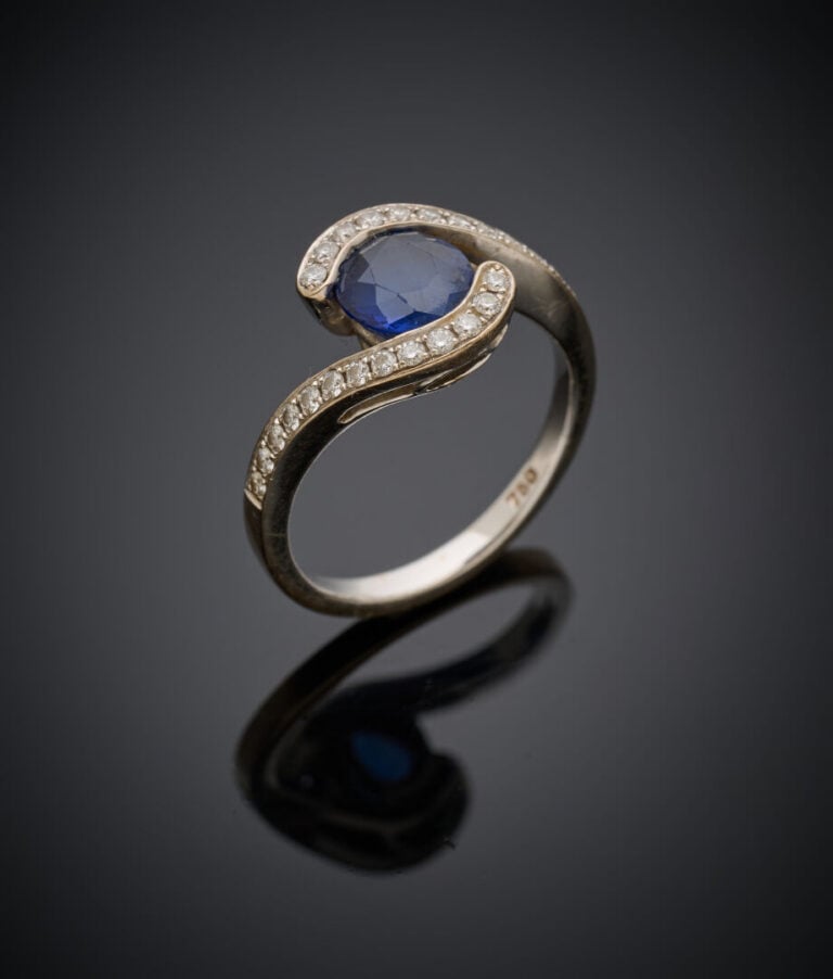 BAGUE sinueuse en or gris (750‰) serti d'un saphir rond (légères égrisures), so…