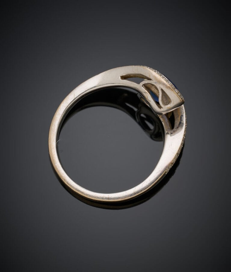 BAGUE sinueuse en or gris (750‰) serti d'un saphir rond (légères égrisures), so…
