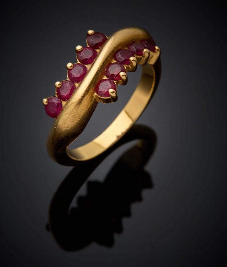 BAGUE sinueuse en or jaune (750‰) serti d'alignements de dix rubis ronds. - Tra…