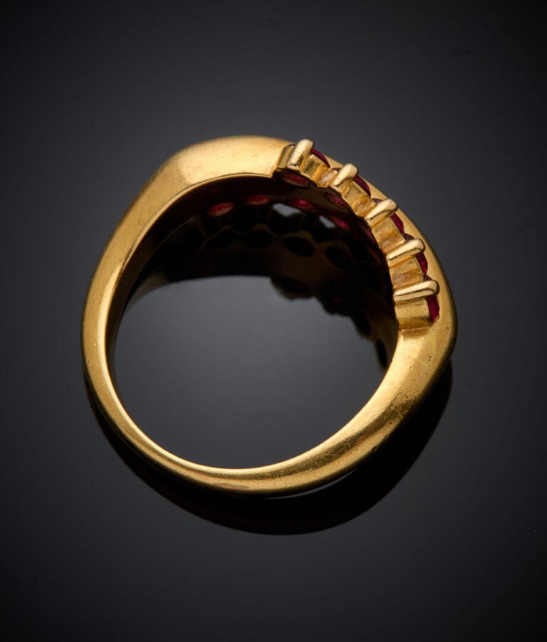 BAGUE sinueuse en or jaune (750‰) serti d'alignements de dix rubis ronds. - Tra…