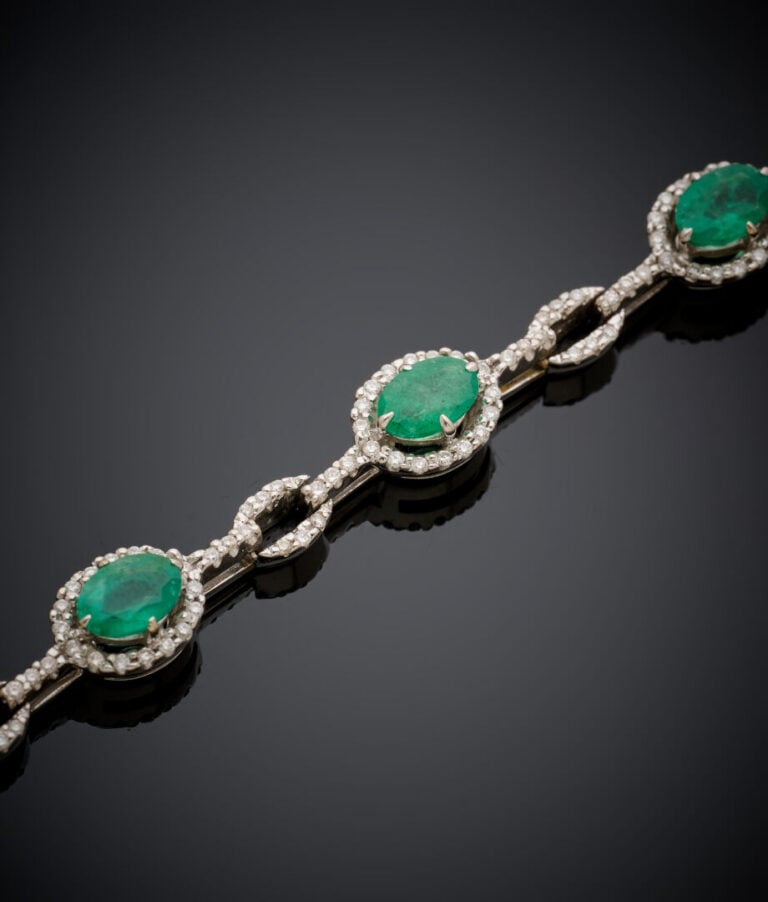 BRACELET articulé en or gris (750‰) serti d'émeraudes ovales entourées de diama…