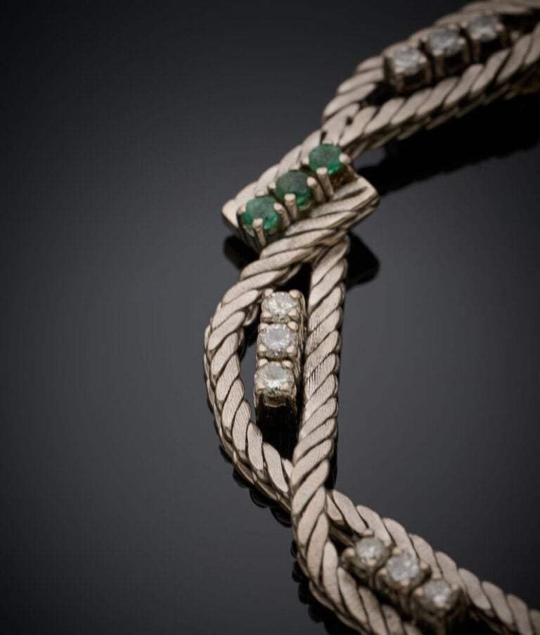 BRACELET en or gris (750‰) torsadé ponctué de diamants taille brillant et d'éme…