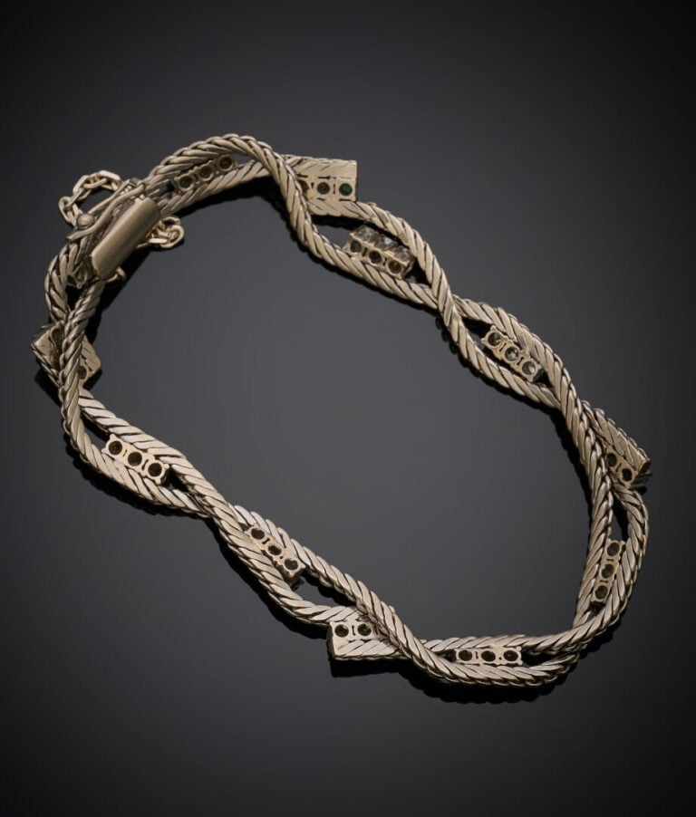 BRACELET en or gris (750‰) torsadé ponctué de diamants taille brillant et d'éme…