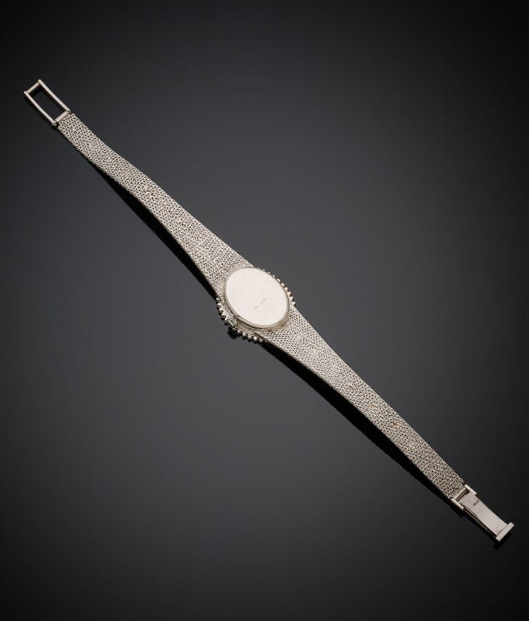BRACELET MONTRE ovale de dame en or gris (750‰). Lunette sertie de petits amant…